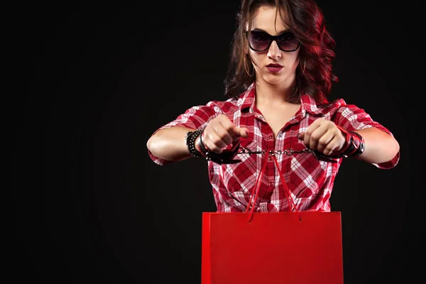 Venerdì nero concetto di vendita. Donna che tiene borse isolate su sfondo scuro. Ragazza ammanettata legata alla borsa. Ostaggio dello shopping e delle vendite . — Foto Stock