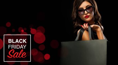 Kara Cuma indirim konsepti. Gri çantalı alışveriş yapan kadın tatilde karanlık arka planda izole edilmiş.