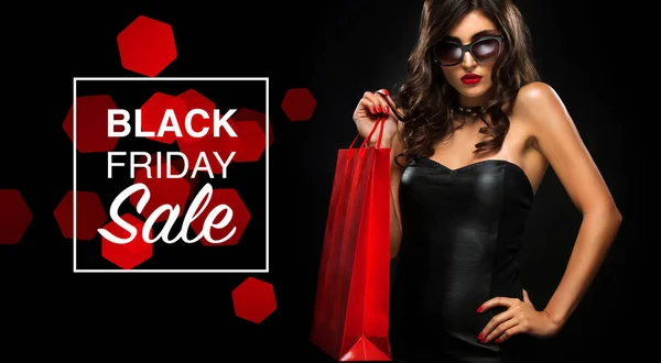 Viernes negro concepto de venta. Mujer de compras sosteniendo bolsa roja aislada sobre fondo oscuro en vacaciones — Foto de Stock