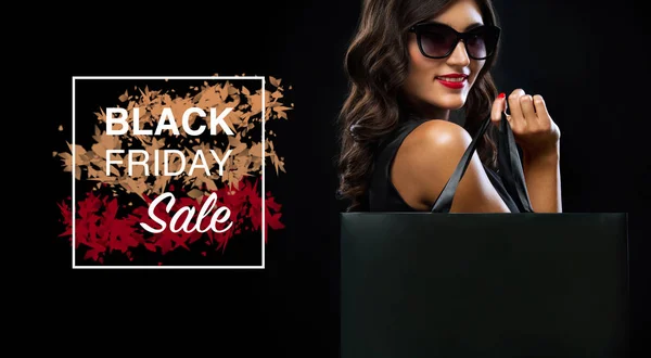 Black friday sale concept. Shopping woman holding grey bag isolated on dark background in holiday — Stock Photo, Image