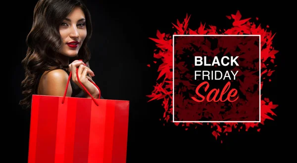 Conceptul de vânzare Black Friday. O femeie care deține geanta roșie izolată pe fundal întunecat în vacanță — Fotografie, imagine de stoc
