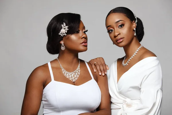 Due belle e felici donne di pelle nera. Affascinante giovane sposa in abito da sposa e gioielli . — Foto Stock