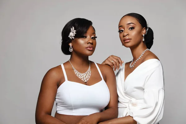 Due belle e felici donne di pelle nera. Affascinante giovane sposa in abito da sposa e gioielli . — Foto Stock