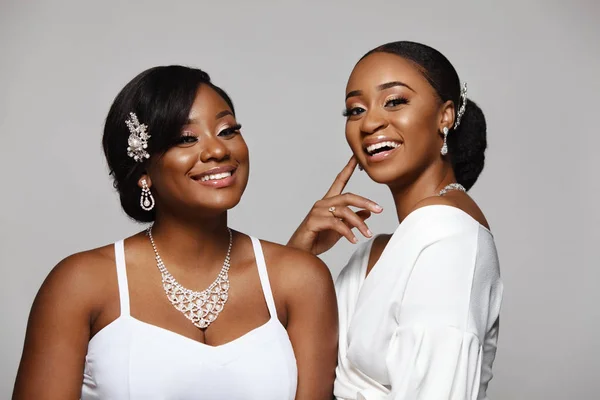 Two happy and beautiful black skin woman. Charming young bride in wedding dress and jewelry. — Stock Photo, Image