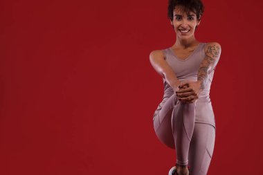 Fitness ve spor motivasyon... Güçlü ve uygun atletik, kadın dövme kırmızı arka planda spor giyim poz ile.