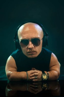 Kulaklık ve mikrofon ile poz güneş gözlüğü ile şık cüce Mc portresi.