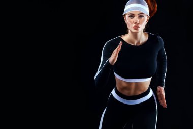 Güçlü bir atletik, siyah arka planda koşan, dar ve formalı bir bayan..