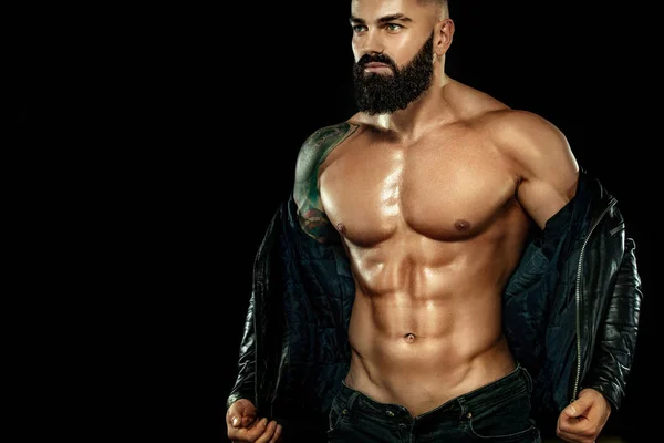 Concetto moda uomo. Ritratto ravvicinato di un brutale uomo barbuto in topless con una giacca di pelle. Atleta bodybuilder su sfondo nero . — Foto Stock