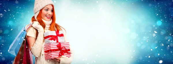 Natal e feriados de Ano Novo. Mulher readhead feliz com presentes. Mulher de compras segurando caixas de presente no fundo do inverno com neve. Cartaz de venda com espaço de cópia . — Fotografia de Stock