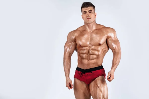 Brutale forte bodybuilder atleta uomo muscolare pompaggio su muscoli su sfondo bianco. Allenamento concetto di bodybuilding. Copia spazio per gli annunci nutrizionali sportivi . — Foto Stock