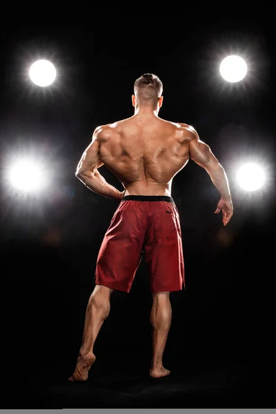 Brutal fuerte musculoso culturista atleta hombre bombeando los músculos sobre fondo negro. Concepto de culturismo de entrenamiento. Espacio de copia para anuncios de nutrición deportiva . — Foto de Stock