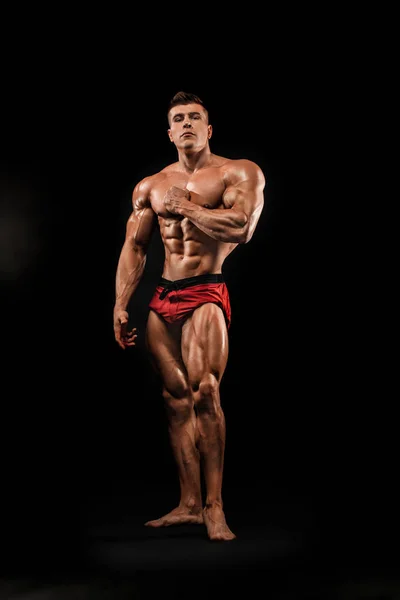 Brutale starke muskulöse Bodybuilder Athlet Mann, der Muskeln auf schwarzem Hintergrund aufpumpt. Workout Bodybuilding Konzept. Kopierraum für Sporternährungsanzeigen. — Stockfoto