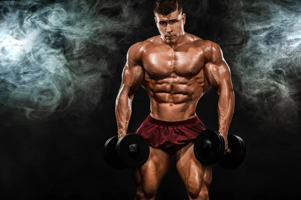 Brutal forte musculoso homem atlético fisiculturista bombeando os músculos com halteres no fundo preto. Conceito de musculação treino. Espaço de cópia para anúncios de nutrição esportiva . — Fotografia de Stock