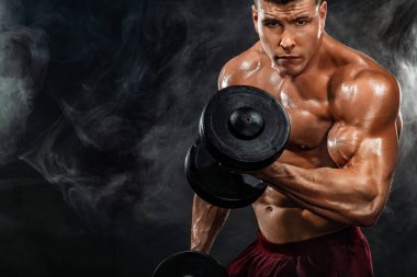 Acımasız güçlü kas vücut geliştirmeci atletik erkek siyah arka plan üzerine dumbbell ile kasları kadar pompalama. Egzersiz vücut geliştirme kavramı. Spor beslenme reklamlar için kopya alanı.