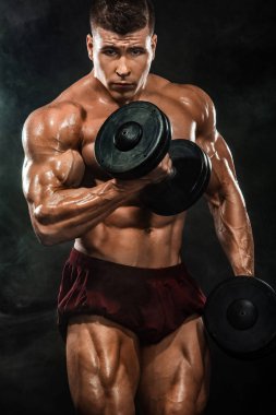 Acımasız güçlü kas vücut geliştirmeci atletik erkek siyah arka plan üzerine dumbbell ile kasları kadar pompalama. Egzersiz vücut geliştirme kavramı. Spor beslenme reklamlar için kopya alanı.