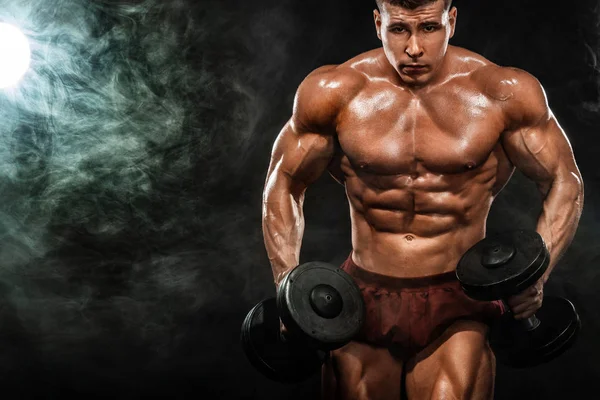 Brutal forte musculoso homem atlético fisiculturista bombeando os músculos com halteres no fundo preto. Conceito de musculação treino. Espaço de cópia para anúncios de nutrição esportiva . — Fotografia de Stock