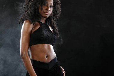 Sportif uygun siyah deri kadın, atlet koyu arka plan üzerinde egzersiz fitness yapar..