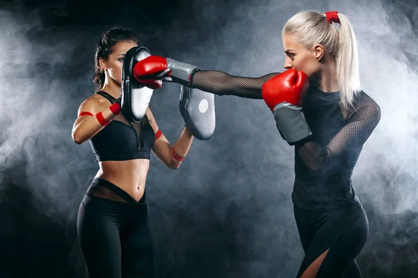Duas mulheres atleta e boxeador trainging antes da luta em fundo preto. Esporte e boxe conceito . — Fotografia de Stock