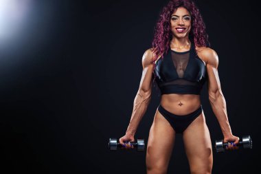 İlk Mısır ve Müslüman kadın atlet dumbbells ile ışıklı siyah arka plan üzerinde egzersiz fitness yapar.