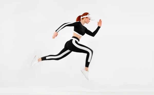 Starke athletische Sprinterin, die auf weißem Hintergrund in Sportkleidung läuft. Fitness und Sportmotivation. Runner-Konzept mit Kopierraum. — Stockfoto