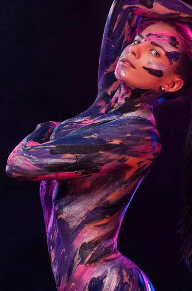 Portrait of woman with colorful body art painted different colors. Inspired dance to music. An amazing woman with art fashion makeup.