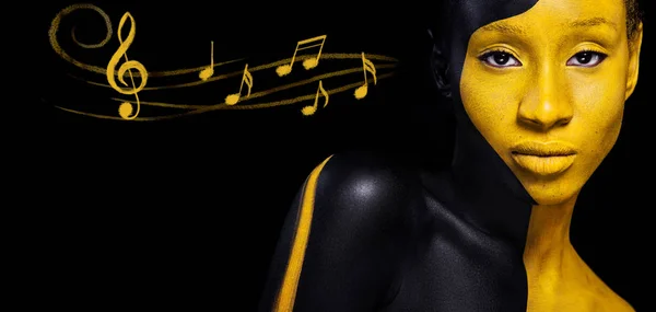 Woman with black body paint. Cheerful young african girl with art  bodypaint. An amazing model with yellow makeup. Closeup face. Stock Photo