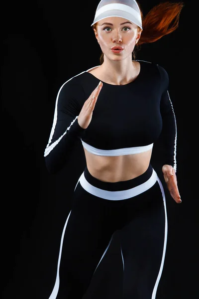 Sterke sportieve vrouw sprinter, uitgevoerd op zwarte achtergrond dragen in sportkleding. Fitness en sport motivatie. Concept met kopie ruimte uitvoeren. — Stockfoto