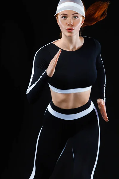 Fuerte atleta mujer velocista, corriendo sobre fondo negro usando ropa deportiva. Fitness y motivación deportiva. Ejecutar concepto con espacio de copia . — Foto de Stock