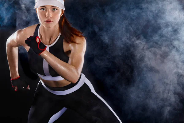 Sterke sportieve vrouw sprinter, uitgevoerd op zwarte achtergrond dragen in de sportkleding. Fitness en sport motivatie. Loper concept met kopie ruimte. — Stockfoto