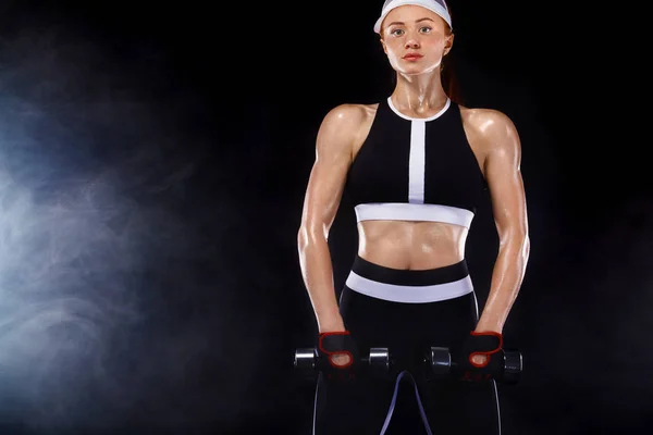 Donna in forma sportiva, atleta con manubri fare esercizi di fitness su sfondo nero . — Foto Stock