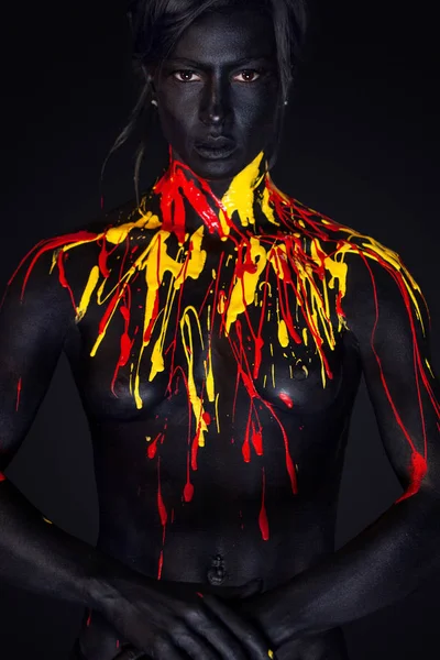 Woman with black body paint. Cheerful young african girl with art  bodypaint. An amazing model with yellow makeup. Closeup face. Stock Photo