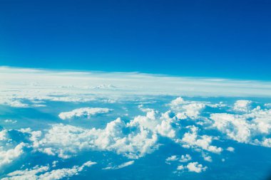 Beyaz Bulutların arasında mavi gökyüzünde uçan uçak