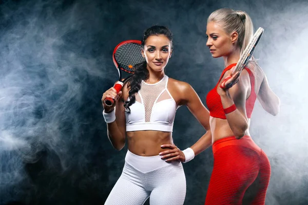 Zwei Sportlerinnen und Tennisspielerinnen auf schwarzem Hintergrund. Sport- und Tenniskonzept. — Stockfoto