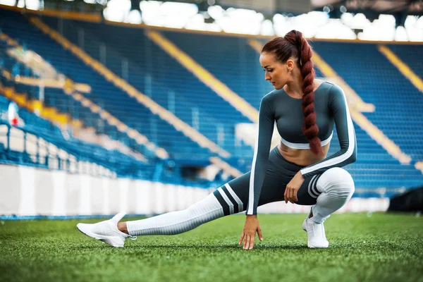 Mulher de fitness no estádio. Estilo de vida desportivo saudável. Atlético jovem do sexo feminino em roupas esportivas fazendo exercício de fitness — Fotografia de Stock