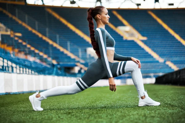Donna in forma allo stadio. Stile di vita sportivo sano. Atletica giovane donna in abbigliamento sportivo facendo esercizio di fitness — Foto Stock