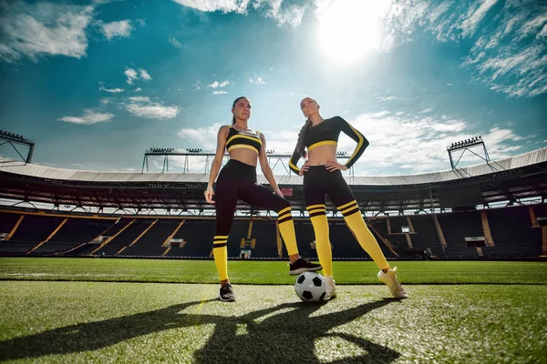 Duas mulheres atléticas esportivas de um time em sportswear com bola de futebol no estádio . — Fotografia de Stock