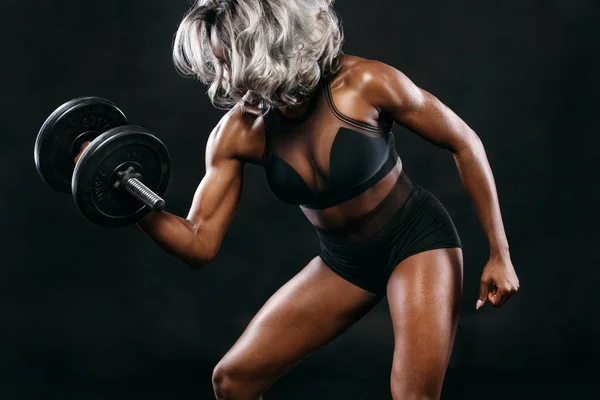 Sporty bella donna di pelle nera con manubri rende l'esercizio di fitness su sfondo scuro per rimanere in forma. Concetto sportivo . — Foto Stock