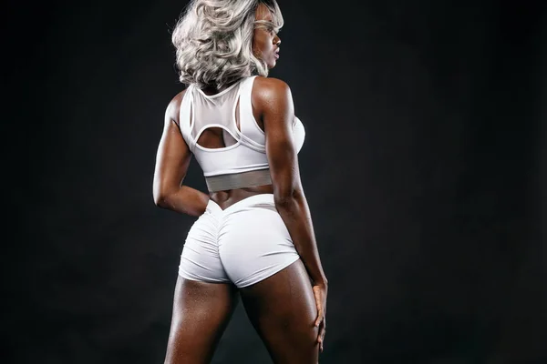 Sportig vackra afro-american bodybuilder modell, kvinna i sportskläder gör fitness träningen på svart bakgrund bo passar — Stockfoto
