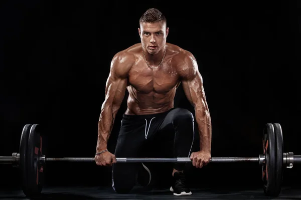 Φωτογραφία: ισχυρό μυώδες bodybuilder αθλητικός άνδρας άντληση τους μυς με barbell σε μαύρο φόντο. Ενέργειας προπόνηση bodybuilding έννοια. — Φωτογραφία Αρχείου