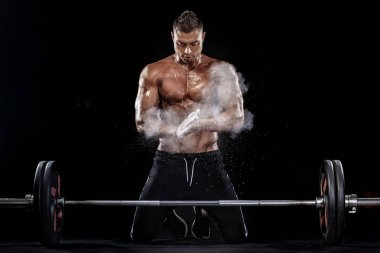 Güçlü kas vücut geliştirmeci atletik erkek siyah arka plan üzerinde halter ile kasları kadar pompalama fotoğraf. Egzersiz enerji vücut geliştirme kavramı.