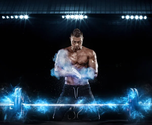 Foto eines kräftigen muskulösen Bodybuilders athletischer Mann, der Muskeln mit Langhantel auf schwarzem Hintergrund mit Lichtern aufpumpt. Workout Energy Bodybuilding Konzept. — Stockfoto
