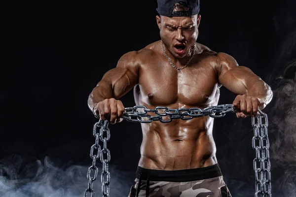 Muscular fitness sports man, atlete with chains in fitness gym. Energy and power.