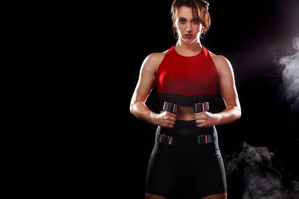 Deportiva mujer en forma, atleta con mancuernas hacer ejercicios de fitness sobre fondo negro . — Foto de Stock