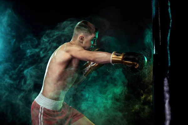 Sportsman, man Boxer slåss i handskar med boxning boxnings påse. Isolerad på svart bakgrund med rök. Kopiera utrymme. — Stockfoto