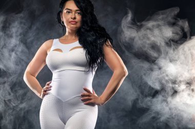 Pretty plump, boyut artı kadın fitness spor salonunda siyah arka planda poz.