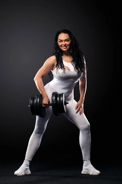 Tamanho mais mulher sporty fit mulher em sportswear branco, atleta com halteres faz exercício de fitness no fundo preto com luzes. Motivação para pessoas gordas . — Fotografia de Stock