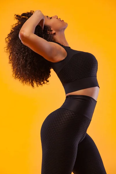 Concepto de estilo de vida. Retrato de hermosa mujer afroamericana feliz y bailando con el pelo rizado. Fondo amarillo del estudio. Copiar espacio . — Foto de Stock