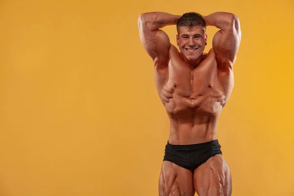 Brutal stark muskulös bodybuilder atlet man pumpa upp muskler på gul bakgrund. Workout Bodybuilding Concept. — Stockfoto