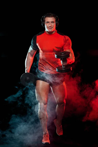 Hombre de deportes de fitness muscular, atleta con mancuerna en gimnasio de fitness. Energía y energía. Corredor y velocista en auriculares . — Foto de Stock