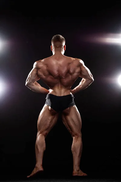 Stark muskulös bodybuilder atlet man poserar och pumpa upp muskler på svart bakgrund. Workout Bodybuilding Concept. — Stockfoto